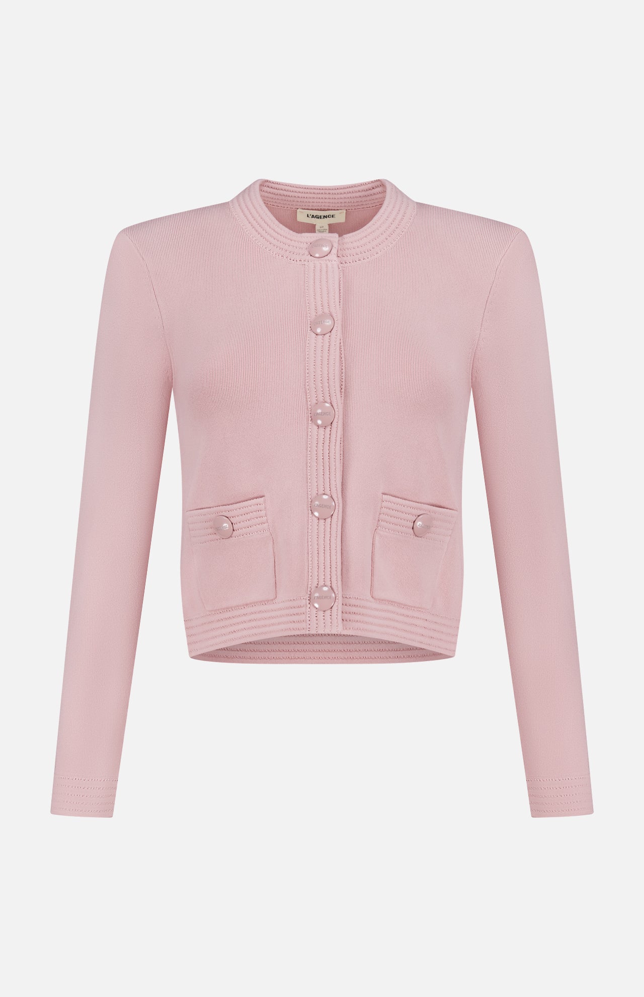 The Patsy Crop Crewneck Cardigan by L'AGENCE is a blush pointelle knit with long sleeves, a round neckline, front buttons, and two small front pockets, shown on a plain white background.
