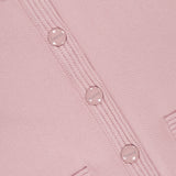 Close-up of the Patsy Crop Crewneck Cardigan by L'AGENCE in blush, featuring round shiny buttons engraved with the brand name, ribbed detailing along the button placket, and the tops of two small front pockets.