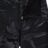 Petite Kendra High Rise Crop Flare in Noir by L’AGENCE features a black coated denim fabric with a metallic sheen, classic five-pocket styling, and a modern cropped flare silhouette. The pants have a partially open zipper and button, revealing a black waistband label that reads L’AGENCE.
