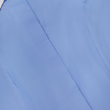 Close-up of the Rina Collared Halter Top by L'AGENCE in light blue poplin, featuring a white pointed collar; shown from an angle highlighting the front and part of the sleeve. The top is neatly pressed and buttoned.