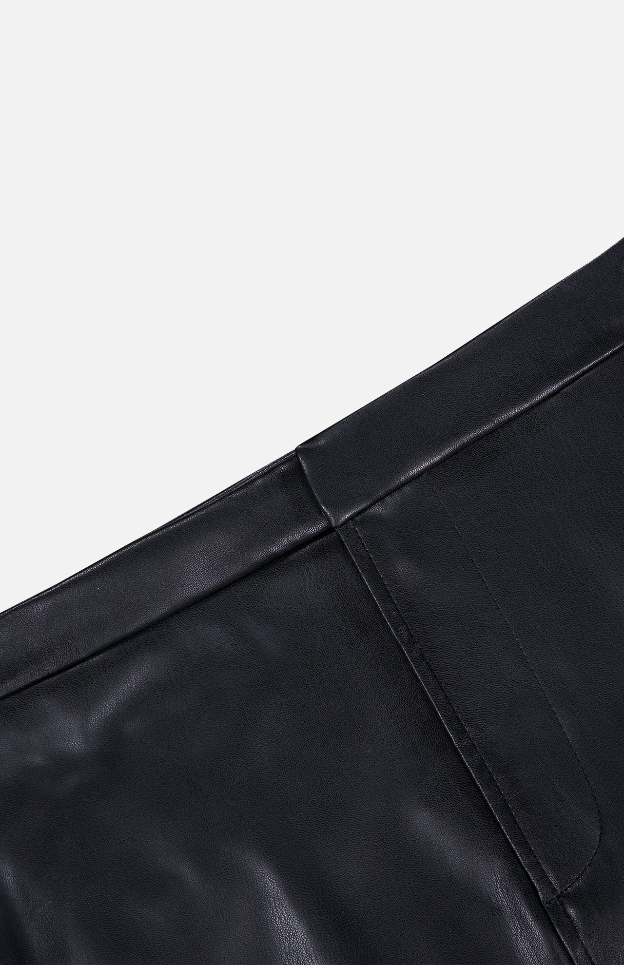 Close-up of the black vegan leather L’Agence Robyn Aline Midi Skirt, featuring a fitted waistband and a vertical seam.