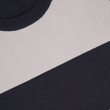 Close-up of the L'AGENCE Rosemond Crewneck Short Sleeve Bodysuit, featuring wide black and light gray stripes, textured knit fabric, a ribbed collar, contouring fit, and a partial clothing label at the upper left corner.