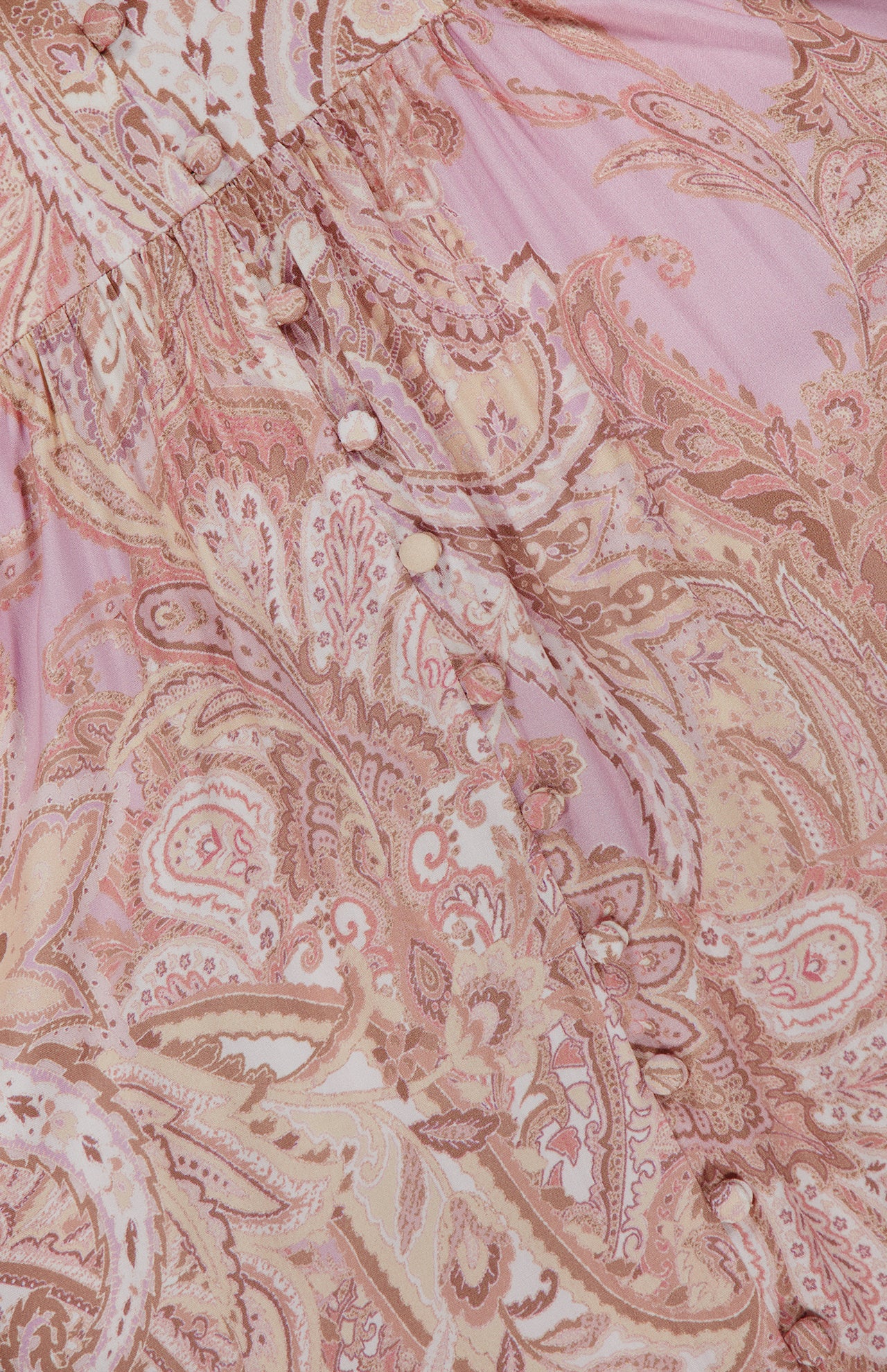 Close-up of the L'AGENCE Rosette Paisley Print Maxi Dress in pink with beige patterns and fabric-covered buttons along a gathered seam on the fitted bodice.