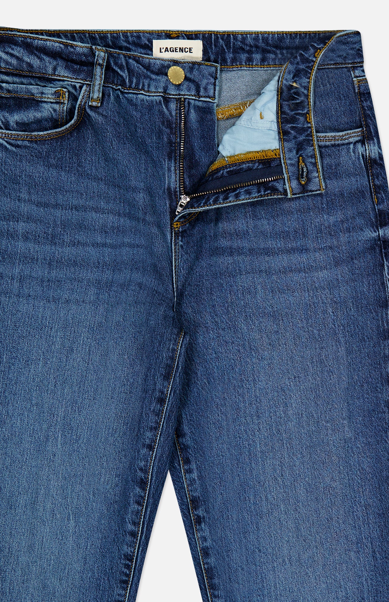 A pair of Ruth High Rise Straight Jeans in Newcastle by L’AGENCE, crafted from premium stretch denim in blue, with the fly unzipped and waistband unbuttoned to reveal the interior fabric and detailed stitching. The L’AGENCE label is visible on the inside waistband. These high-rise jeans offer a timeless straight leg silhouette for effortless style.