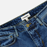 Close-up of the Ruth High Rise Straight Jean in Newcastle by L’AGENCE, crafted from premium stretch denim in blue. These jeans feature yellow stitching, a metal button, belt loops, and a white label with “L’AGENCE” on the inside waistband. The high-rise design and straight leg silhouette offer timeless style and comfort.