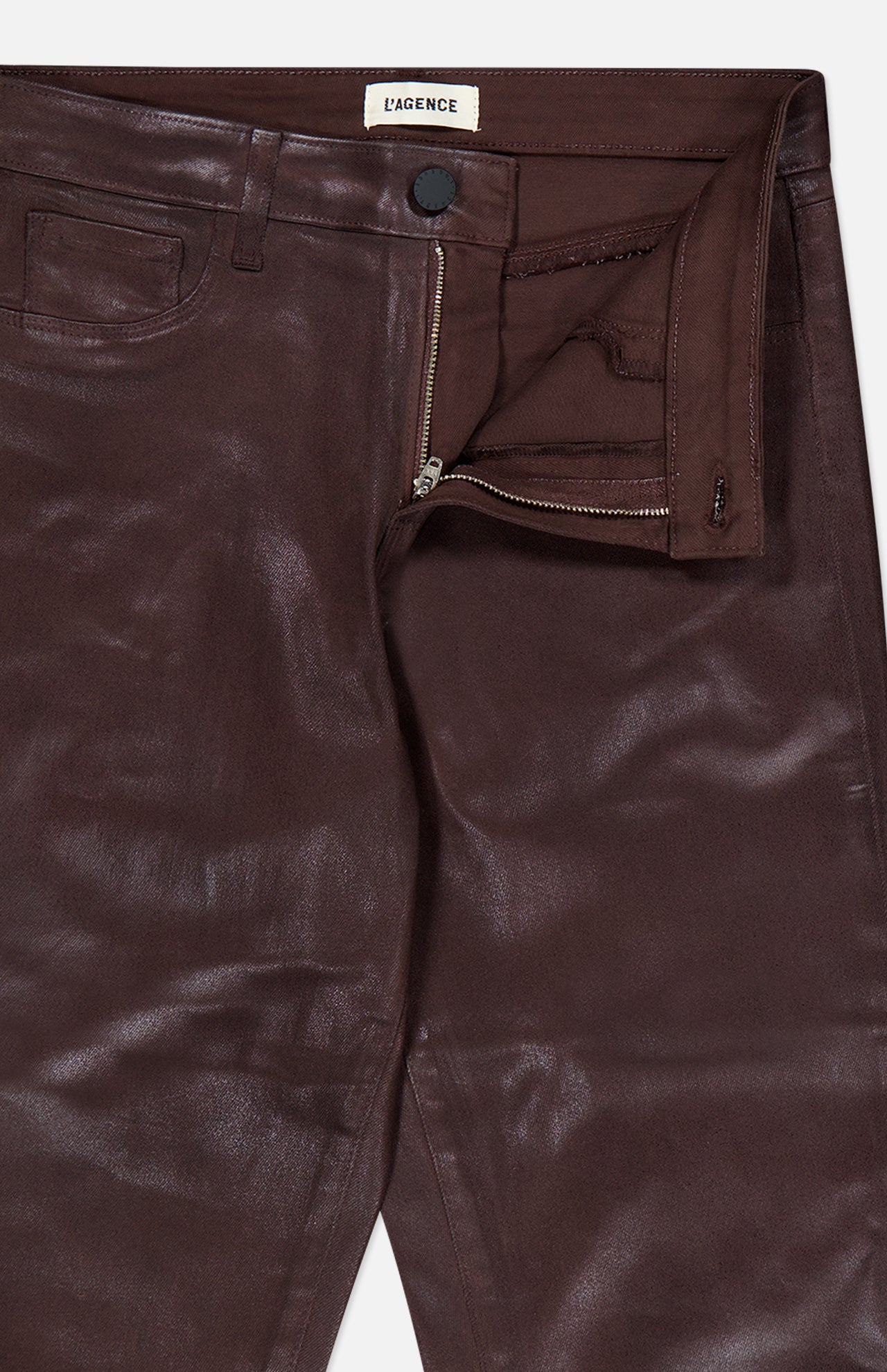 Close-up of the Ruth High Rise Straight Pant by L’AGENCE, crafted from maroon coated denim in a slim straight-leg silhouette with a high rise, partially open zipper fly, visible button, and pocket. The L’AGENCE label is sewn inside the waistband.