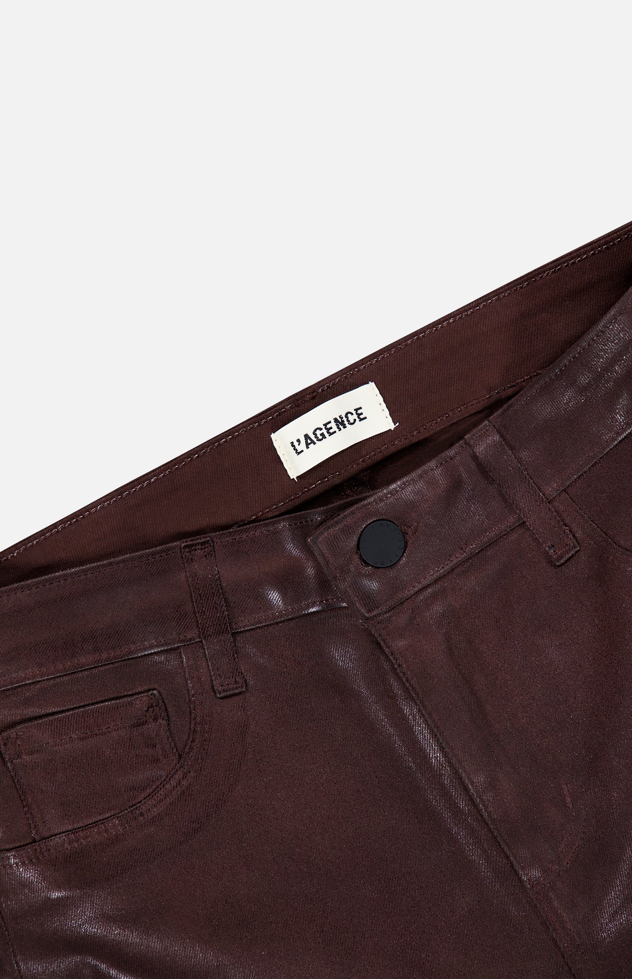 Close-up of shiny burgundy coated Ruth High Rise Straight Pant by L’AGENCE, featuring a black button and visible L’AGENCE label on the inside waistband against a white background; these high-rise pants showcase a slim, straight-leg silhouette.