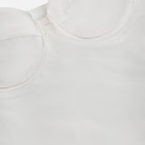 Close-up of the L'AGENCE Saya Cold Shoulder Draped Top in off-white, featuring structured rounded bust cups, smooth satin-like fabric, and visible seam details along the cups and shoulder area.