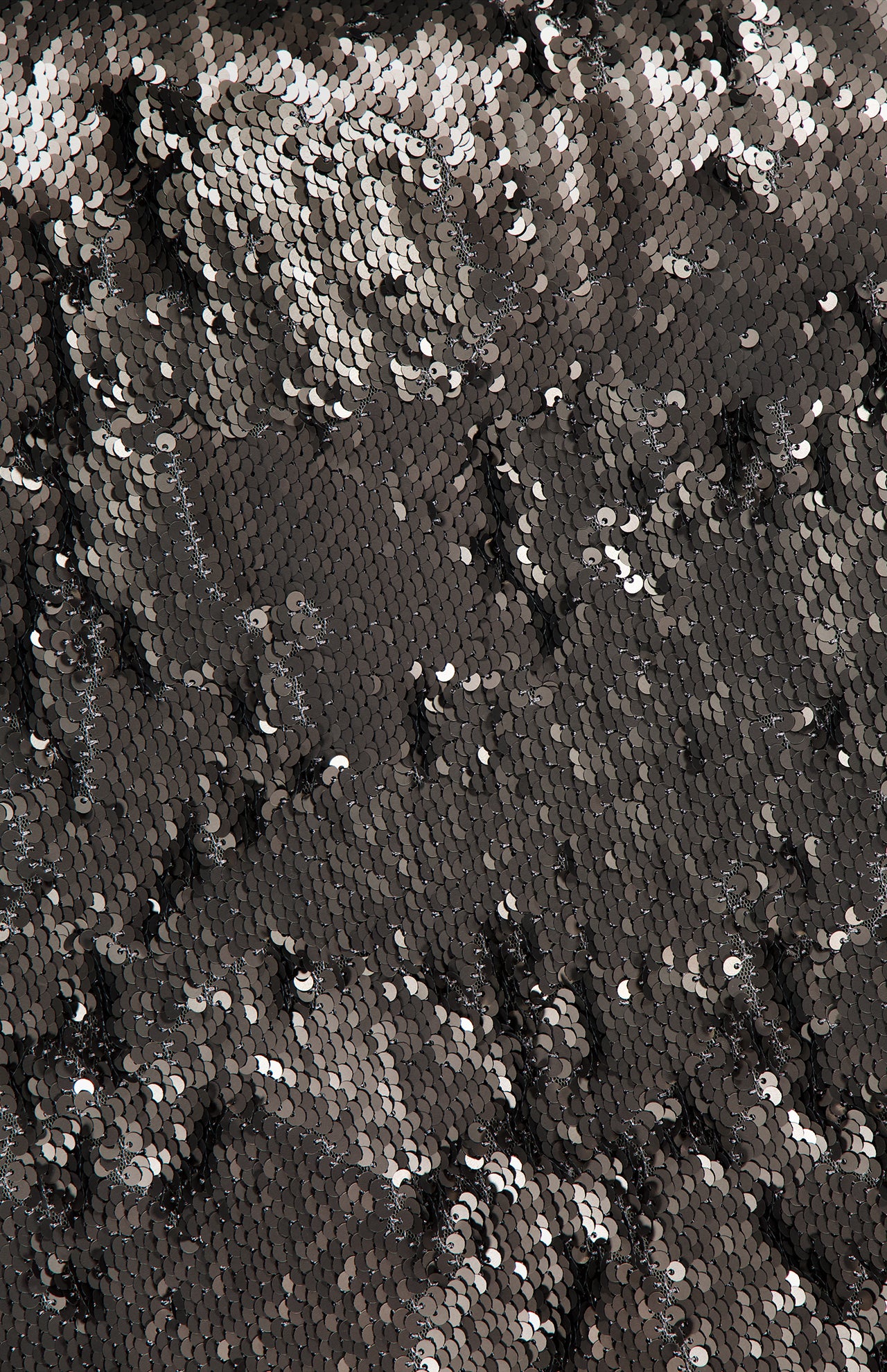 A close-up of the Sayla Bias Cut Sequin Maxi Dress by L'AGENCE showcases its fabric adorned with gleaming black and silver sequins, creating a shimmering, textured surface that radiates vintage glamour—ideal for making a statement at any event.