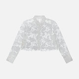 The L'AGENCE Seychelle Cropped Button Down Shirt is a long-sleeve, collared white eyelet top with floral pattern, buttoned cuffs, and semi-sheer fabric, shown on a plain white background.