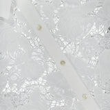Close-up of the Seychelle Cropped Button Down Shirt by L'AGENCE, featuring white eyelet fabric with intricate floral lace, a white buttoned placket, pointed collar, pearl-like buttons, and elegant rose designs.
