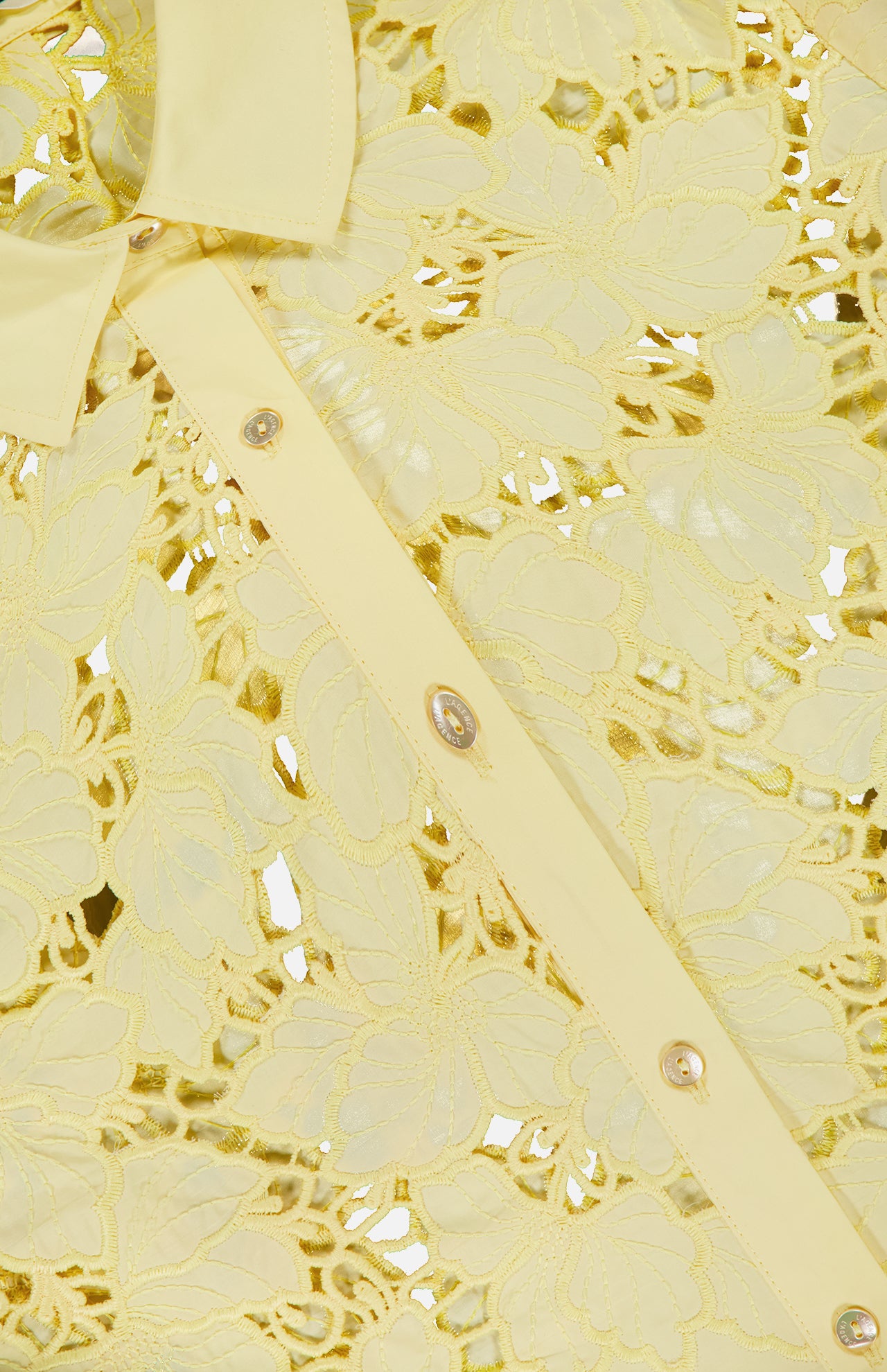 Close-up of the L'AGENCE Seychelle Cropped Button Down Shirt—a yellow summer top with floral embroidery, shiny buttons, a pointed collar, and semi-sheer eyelet fabric for a delicate, feminine look.