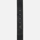A close-up of the L’AGENCE Solera Engraved Plaque Belt showcases its black leather strap with a subtle texture and four round adjustment holes, perfectly complemented by refined silver accessories.