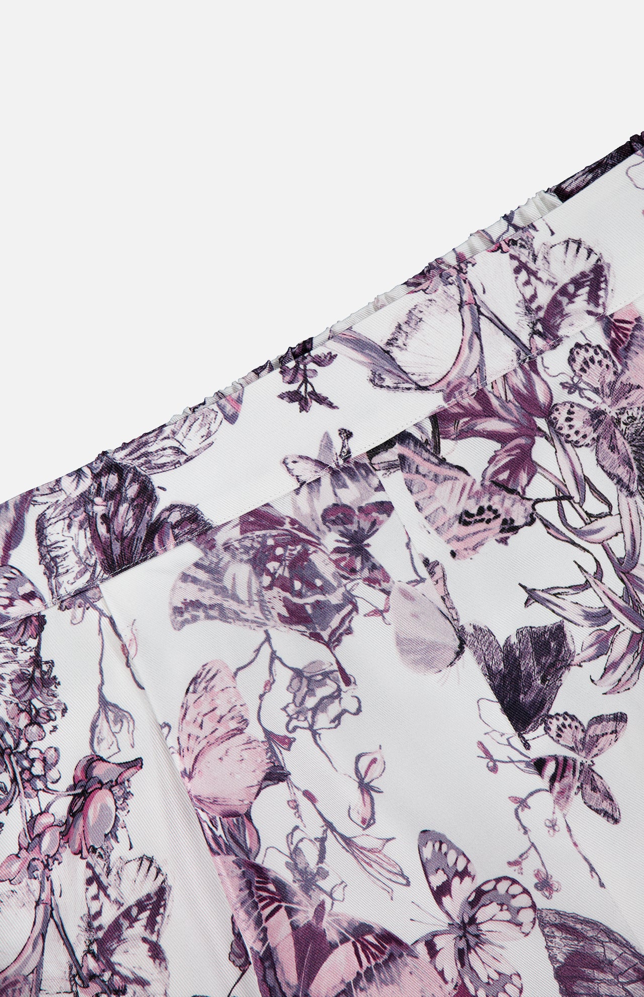 Close-up of the Sylie Butterfly Print Pull On Short by L'AGENCE, showcasing white fabric with pink and purple florals, butterfly motifs, a pleated seam detail, partial waistband, and a comfy pull-on fit.