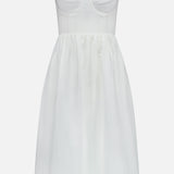 The Tiani Bustier Midi Dress by L'AGENCE is a sleeveless white linen dress with a fitted, bustier-style bodice, adjustable straps, and a flared knee-length skirt for a structured yet simple summer look.
