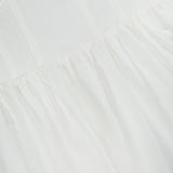 Close-up of the Tiani Bustier Midi Dress by L'AGENCE, featuring a fitted bodice and gathered, flowing skirt in soft white linen with subtle stitching—an ideal breezy summer dress.