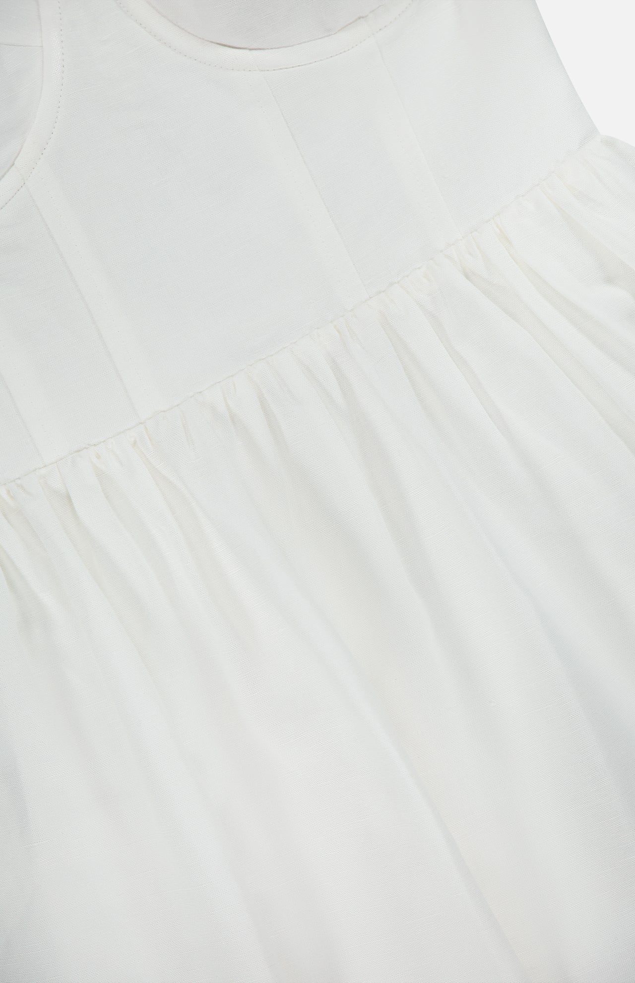 Close-up of the Tiani Bustier Midi Dress by L'AGENCE, featuring a fitted bodice and gathered, flowing skirt in soft white linen with subtle stitching—an ideal breezy summer dress.