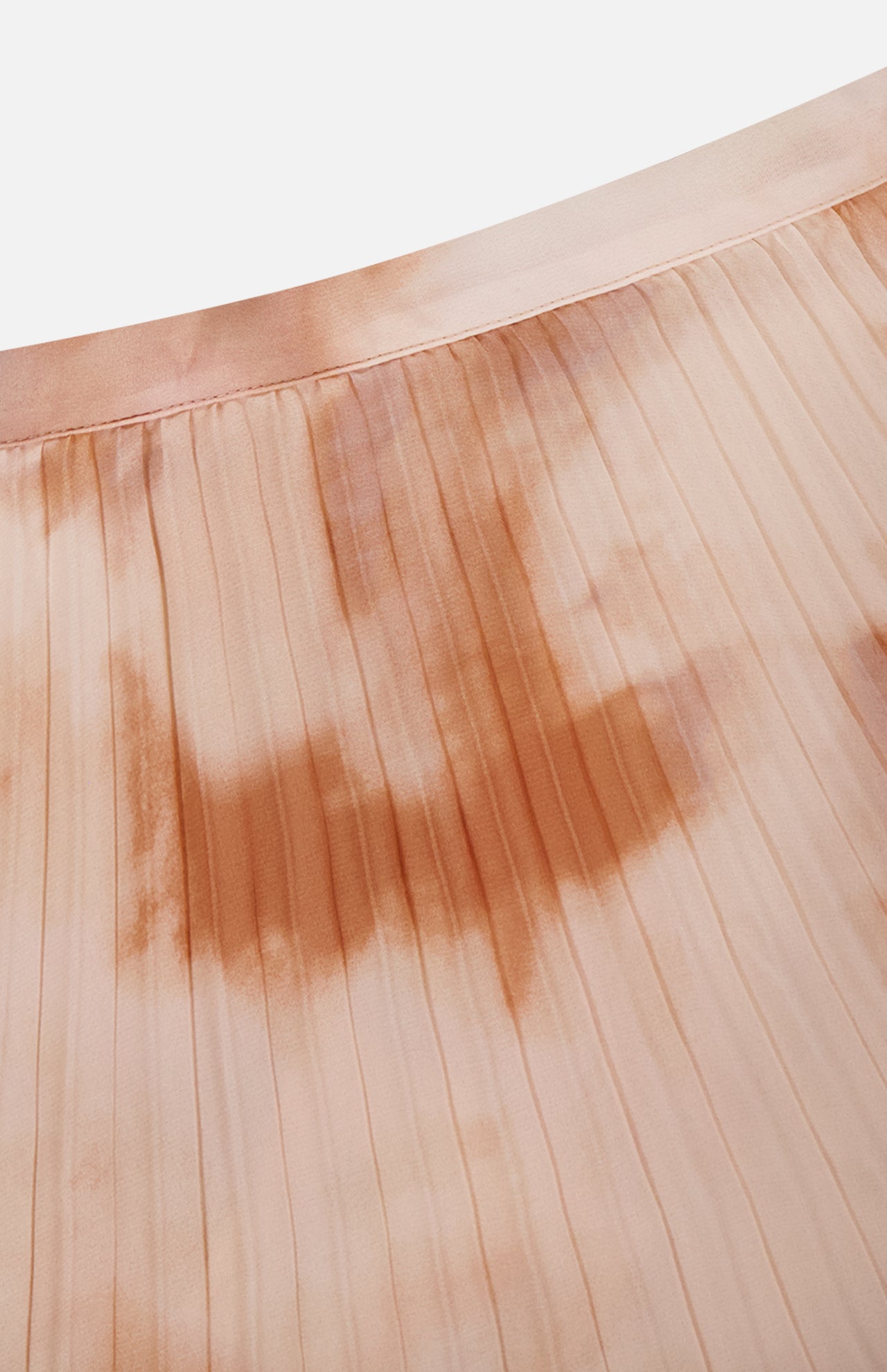 Close-up of the Torin Pleated Maxi Skirt by L'AGENCE in light peach, showcasing subtle brown and pink frappe tie-dye. The soft fabric features evenly spaced vertical pleats and a smooth, slightly glossy finish.
