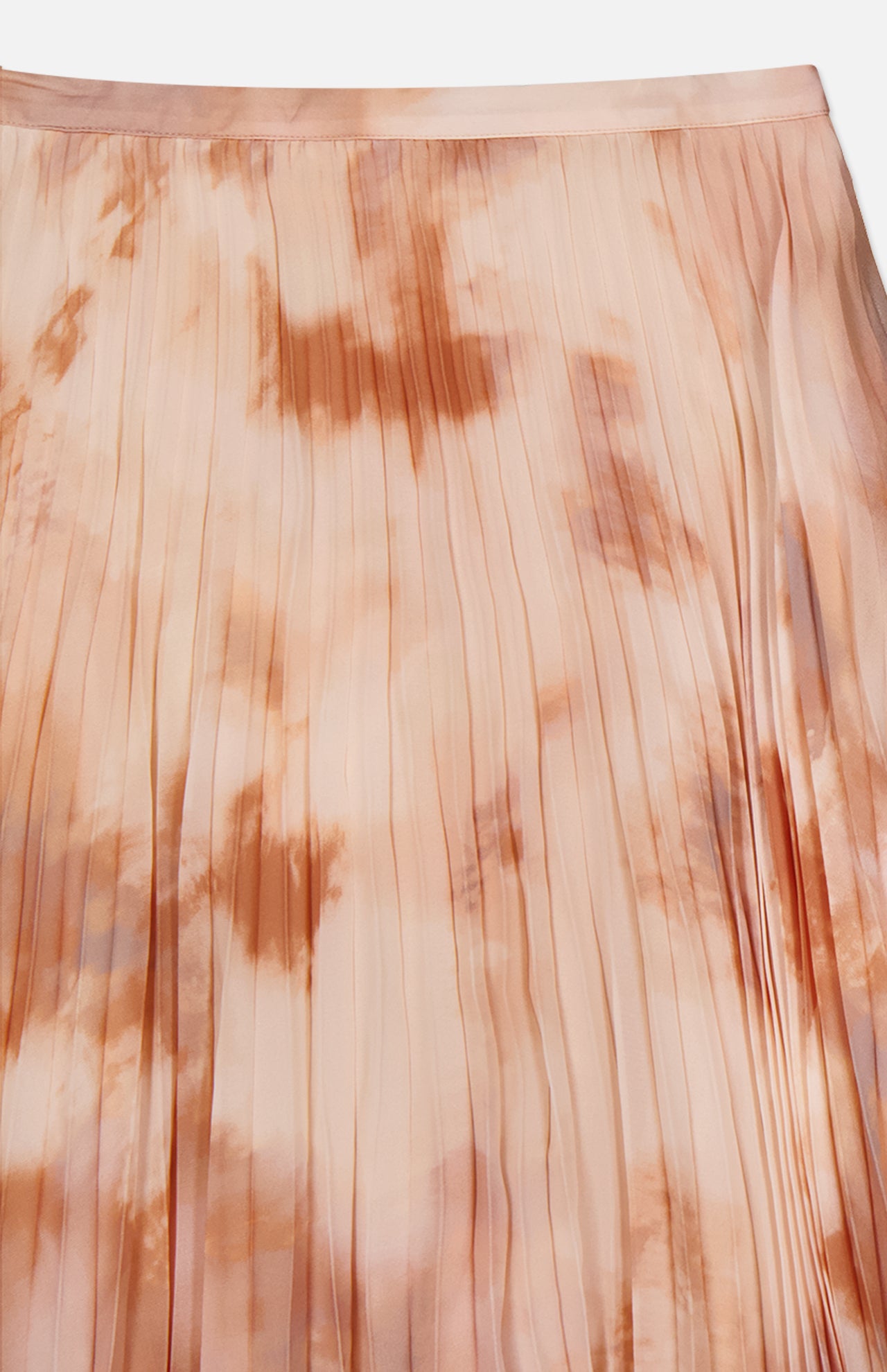 A close-up of the L'AGENCE Torin Pleated Maxi Skirt, featuring vertical pleats and a soft peach and tan frappe tie-dye pattern with delicate color variations.