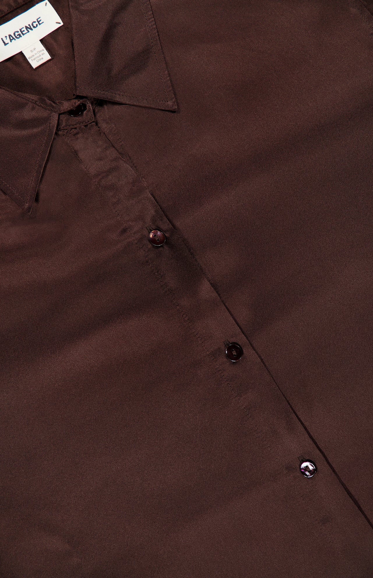 Close-up of a dark brown long-sleeve Tyler Long Sleeve Blouse by L’Agence with a pointed collar.