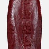 The Violetta Pencil Skirt by L’AGENCE, crafted from burgundy croc-embossed vegan leather, features a front seam and a subtle front slit, showcased against a plain white background.