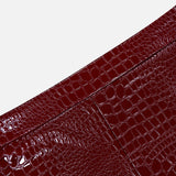 Close-up of the Violetta Pencil Skirt by L’AGENCE, featuring a glossy, dark red croc-embossed vegan leather with a patchwork design, set against a plain white background.