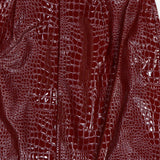 Close-up of the Violetta Pencil Skirt by L’AGENCE, crafted from shiny, croc-embossed vegan leather in dark red, featuring a distinctive embossed texture and a visible vertical seam near the center.