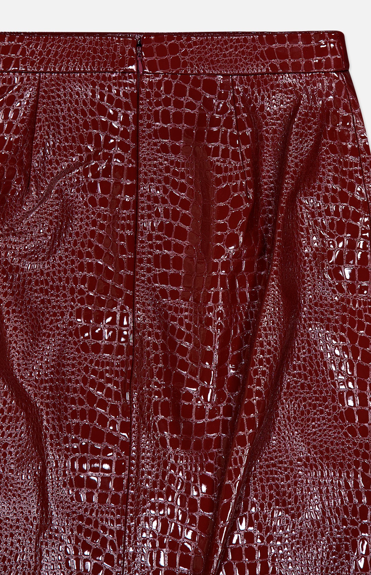 Close-up of the Violetta Pencil Skirt by L’AGENCE, crafted from shiny, croc-embossed vegan leather in dark red, featuring a distinctive embossed texture and a visible vertical seam near the center.
