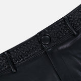 Close-up of the L’AGENCE Virelle Braided Waistband Short in black vegan leather, featuring a textured braided waistband and button closure. The shorts are displayed against a plain, light background.