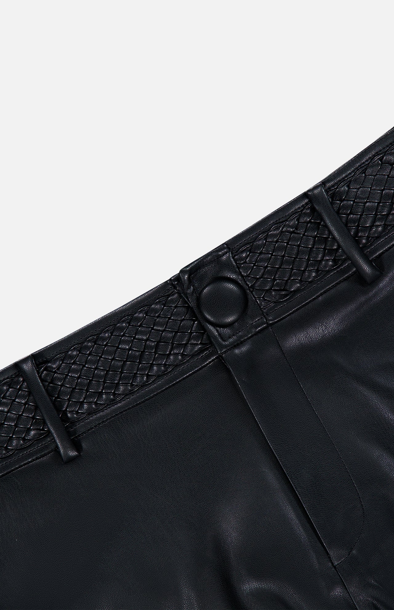 Close-up of the L’AGENCE Virelle Braided Waistband Short in black vegan leather, featuring a textured braided waistband and button closure. The shorts are displayed against a plain, light background.