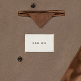 Close-up of the inside of a brown Double Breasted Car Coat by L.B.M., made in Italy, showing a pocket, brown fabric detail, brown buttons, and a white label with the text L.B.M. 1911.