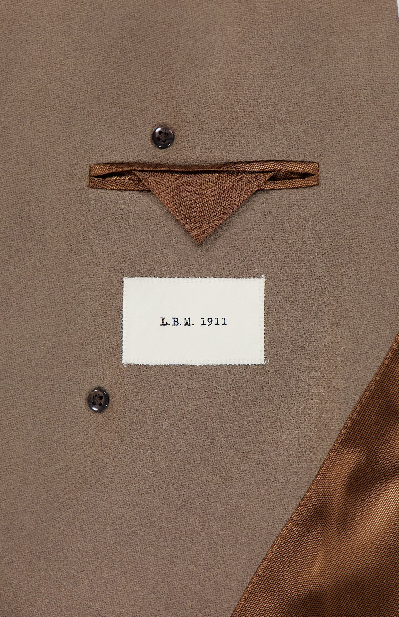Close-up of the inside of a brown Double Breasted Car Coat by L.B.M., made in Italy, showing a pocket, brown fabric detail, brown buttons, and a white label with the text L.B.M. 1911.