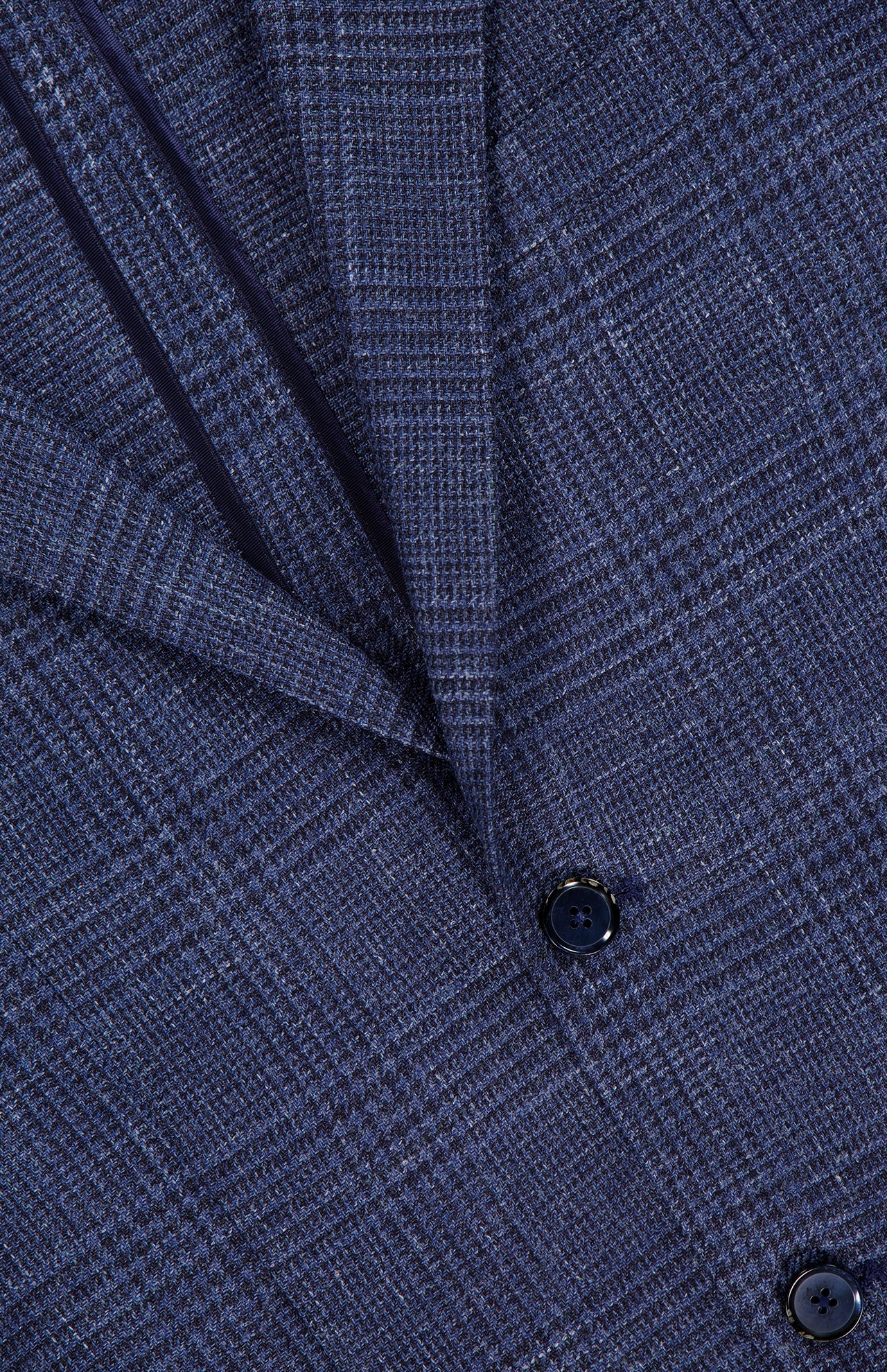 Close-up of the L.B.M. Glen Plaid 2 Button Sportcoat, expertly crafted from a luxurious wool-silk-linen blend, showcasing its textured navy blue glen plaid pattern, classic lapel, and two black buttons.