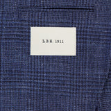 A close-up of the L.B.M. Glen Plaid 2 Button Sportcoat in blue, highlighting its refined wool-silk-linen blend fabric and tailored details, with a small white L.B.M. label above the pocket.