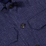 Close-up of the Glen Plaid Overshirt by L.B.M., showcasing a navy plaid pattern with black buttons and two chest pockets. The soft texture suggests the premium quality of this men's button-front shirt. The Yellow Fillings Lancaster, PA label is visible on the inside collar.