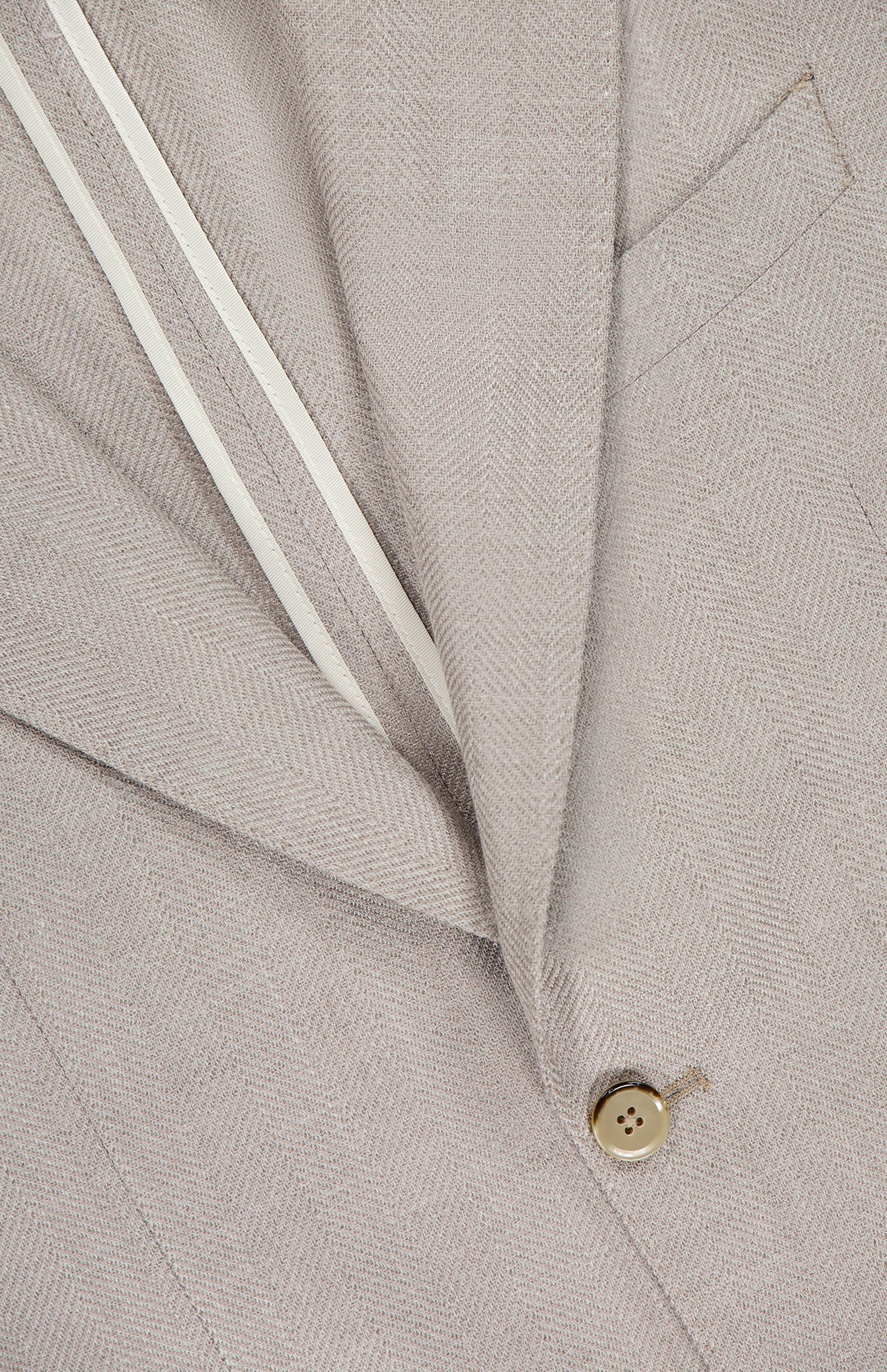 Close-up of the L.B.M. Herringbone Untreated Sportcoat in beige, crafted in Italy from a wool-silk-linen blend, with notched lapel, single button, chest pocket, and white inner lining.