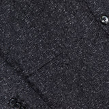 Close-up of the textured dark grey fabric of the L.B.M. Speck 2 Button Sportcoat, highlighting a front pocket, four black sleeve buttons, and two black front buttons arranged diagonally across the image. This modern sportcoat showcases expert L.B.M. craftsmanship for ultimate sophistication and style.