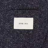 A close-up of the textured dark grey Speck 2 Button Sportcoat by L.B.M., made in Italy, featuring a white sewn-on label with "L.B.M. 1911" in black text.