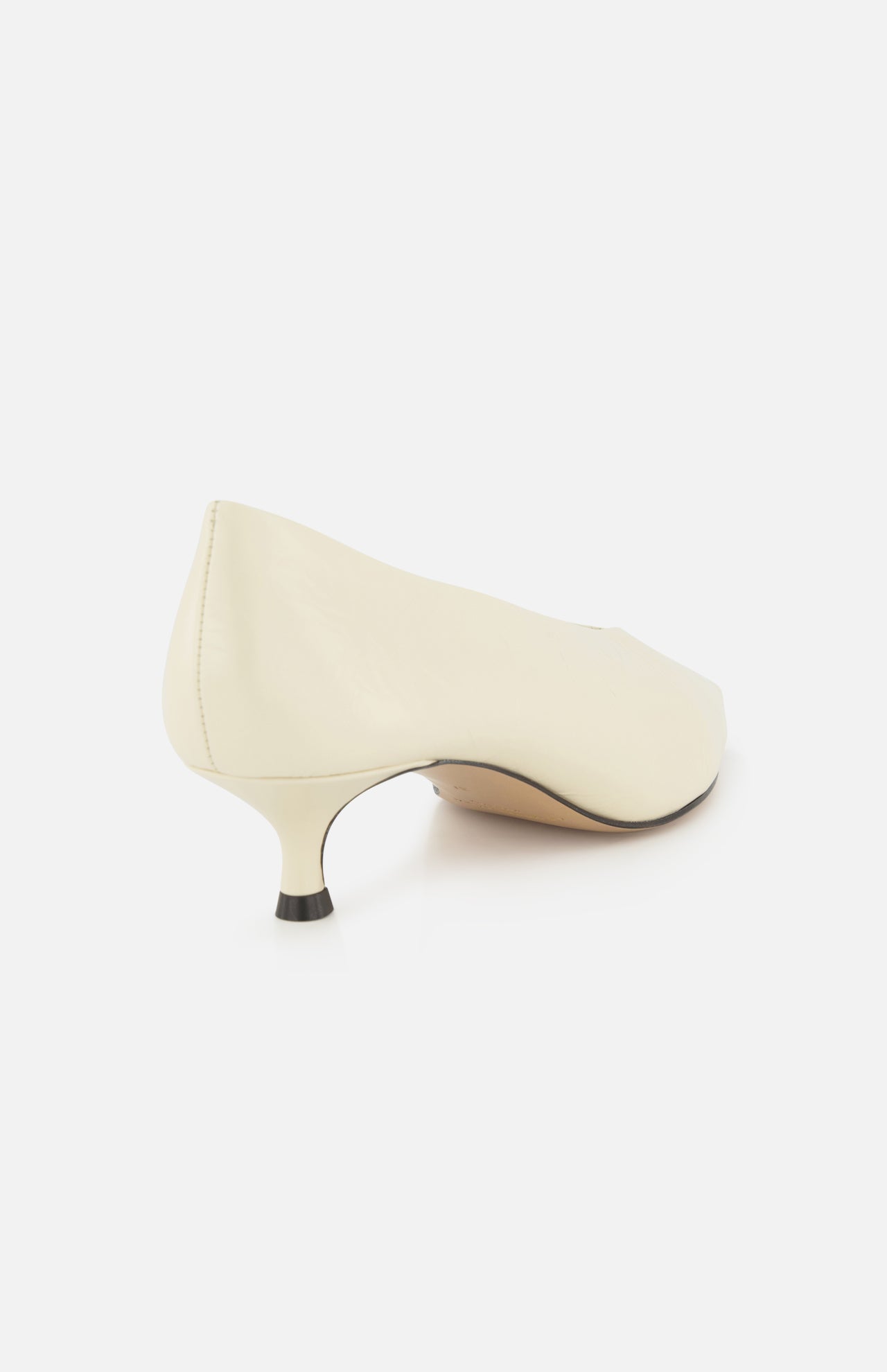 The Babouche Leather Kitten Heel by LE MONDE BERYL is shown from the back, featuring a cream-colored design with a rounded toe and kitten heel against a white background.