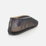 The Luna Mesh Slipper by LE MONDE BERYL is a black mesh flat with a transparent upper and solid black sole, viewed from the rear side on a white background. It features a cushioned calf leather insole for comfort and is handcrafted in Italy.