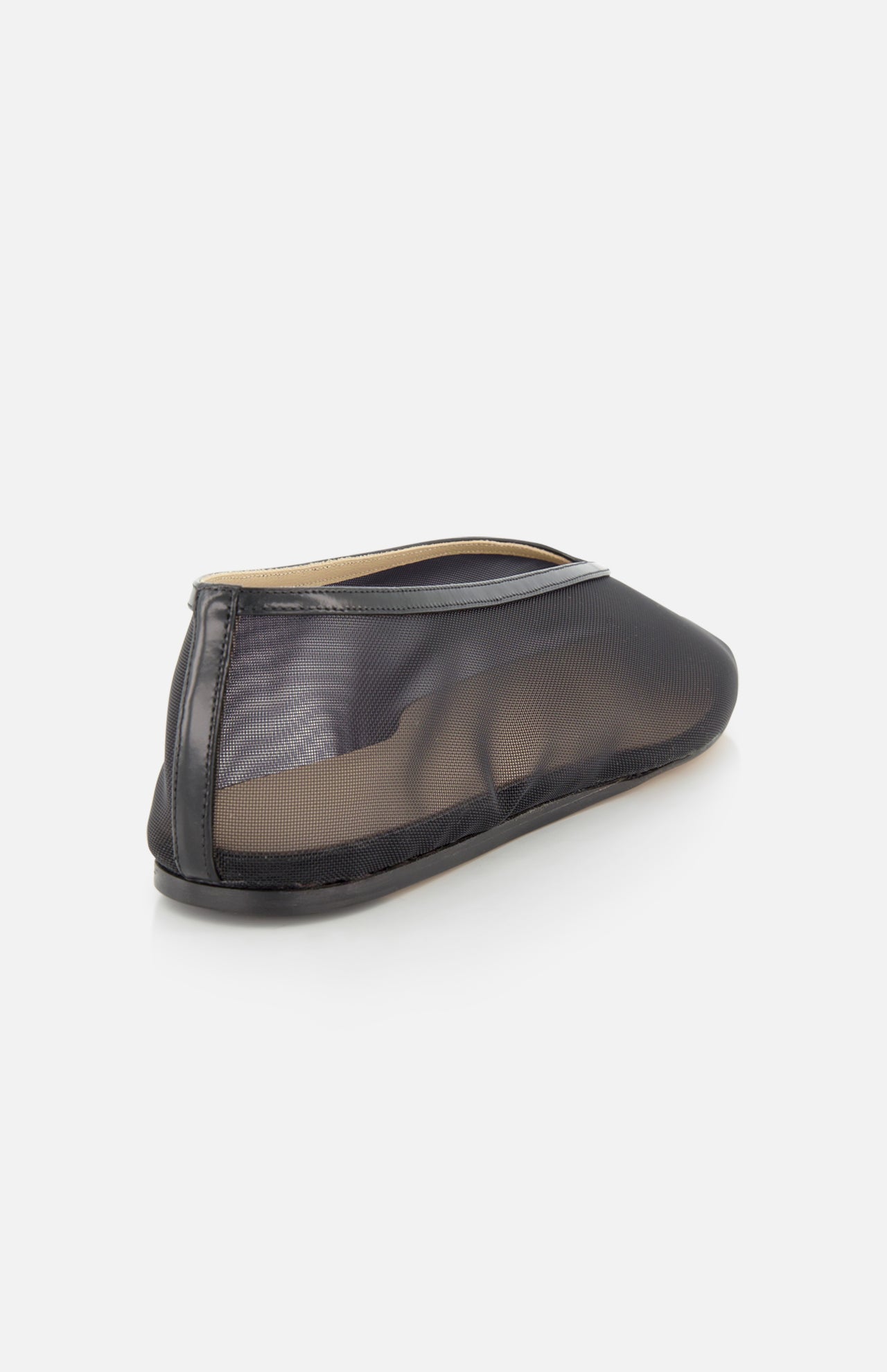 The Luna Mesh Slipper by LE MONDE BERYL is a black mesh flat with a transparent upper and solid black sole, viewed from the rear side on a white background. It features a cushioned calf leather insole for comfort and is handcrafted in Italy.