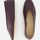 Le Monde Béryl Luna Leather Slipper Flat: a pair of handcrafted dark burgundy leather flat slippers with a V-cut vamp, shown from the top and side.
