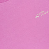 A close-up of the Crew Neck Logo T-shirt by LES DEUX in bright pink, featuring the brand's name stitched in white on the chest and a visible LES DEUX label inside the neckline—ideal for standout casual wear.