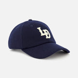 The Felt Logo Dad Cap by LES DEUX is a navy baseball hat with a curved brim, featuring a striking white embroidered LD monogram on the front.