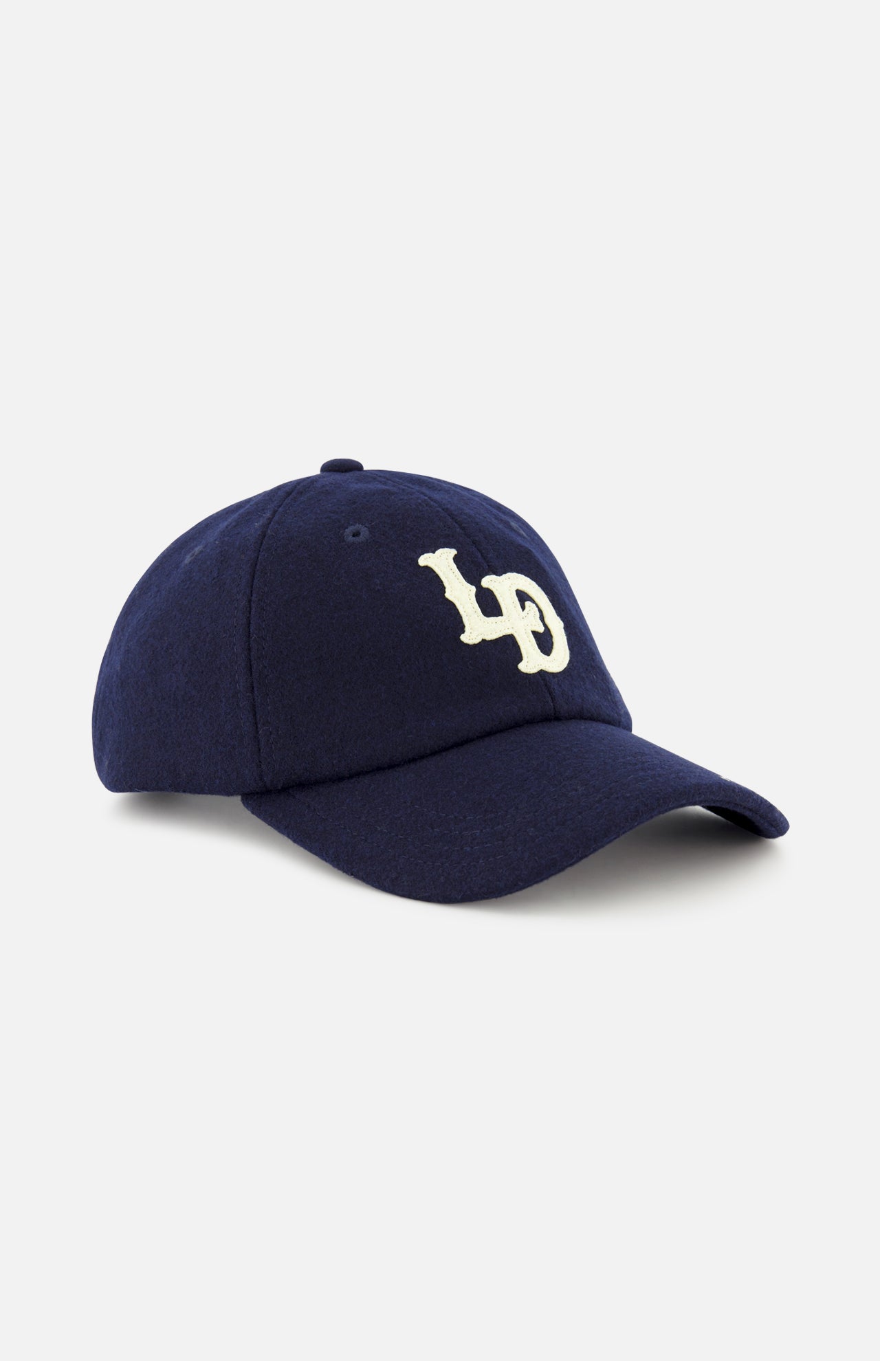 The Felt Logo Dad Cap by LES DEUX is a navy baseball hat with a curved brim, featuring a striking white embroidered LD monogram on the front.