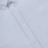 A close-up of the LES DEUX Konrad Striped Oxford Shirt in light blue and white shows white buttons, a small embroidered logo on the chest, and classic stripes.
