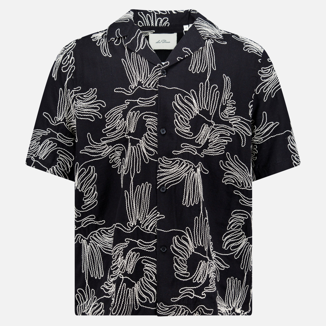 The LES DEUX Liam AOE Flower Short Sleeve Shirt is a boxy, relaxed-fit black cotton shirt with a button-up front, collar, and white abstract handprint pattern, shown on a plain white background.
