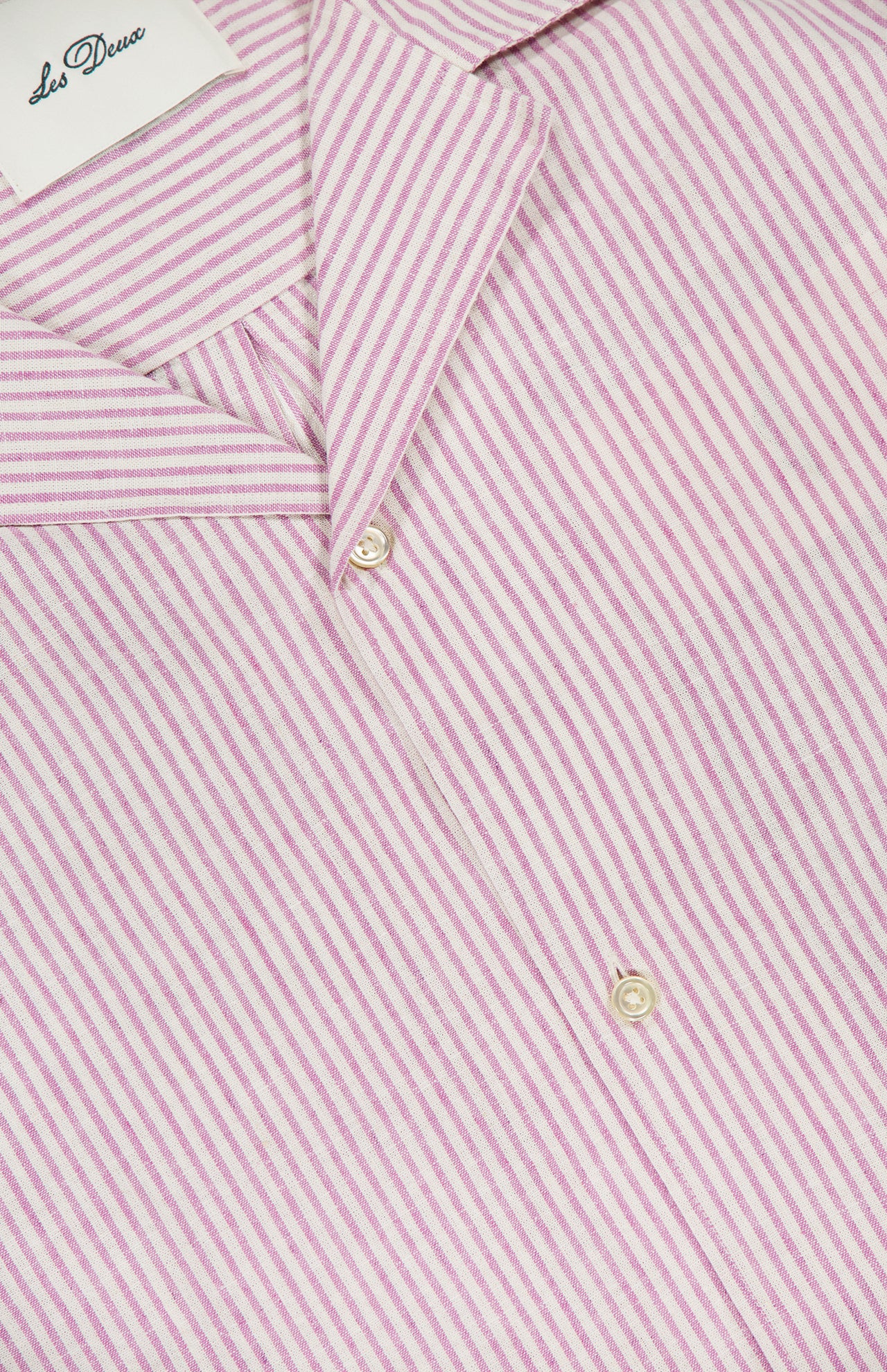 Close-up of the LES DEUX Lukas Stripe Cotton Linen Short Sleeve Shirt in pink with white and light pink stripes, two buttons in view, and a partial white LES DEUX label at the top left.