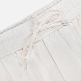 Close-up of the waistband on LES DEUX Patrick Linen-blend Pants, showing breathable light beige fabric, an elastic band with drawstring waist, and a small LES DEUX tag near the top.