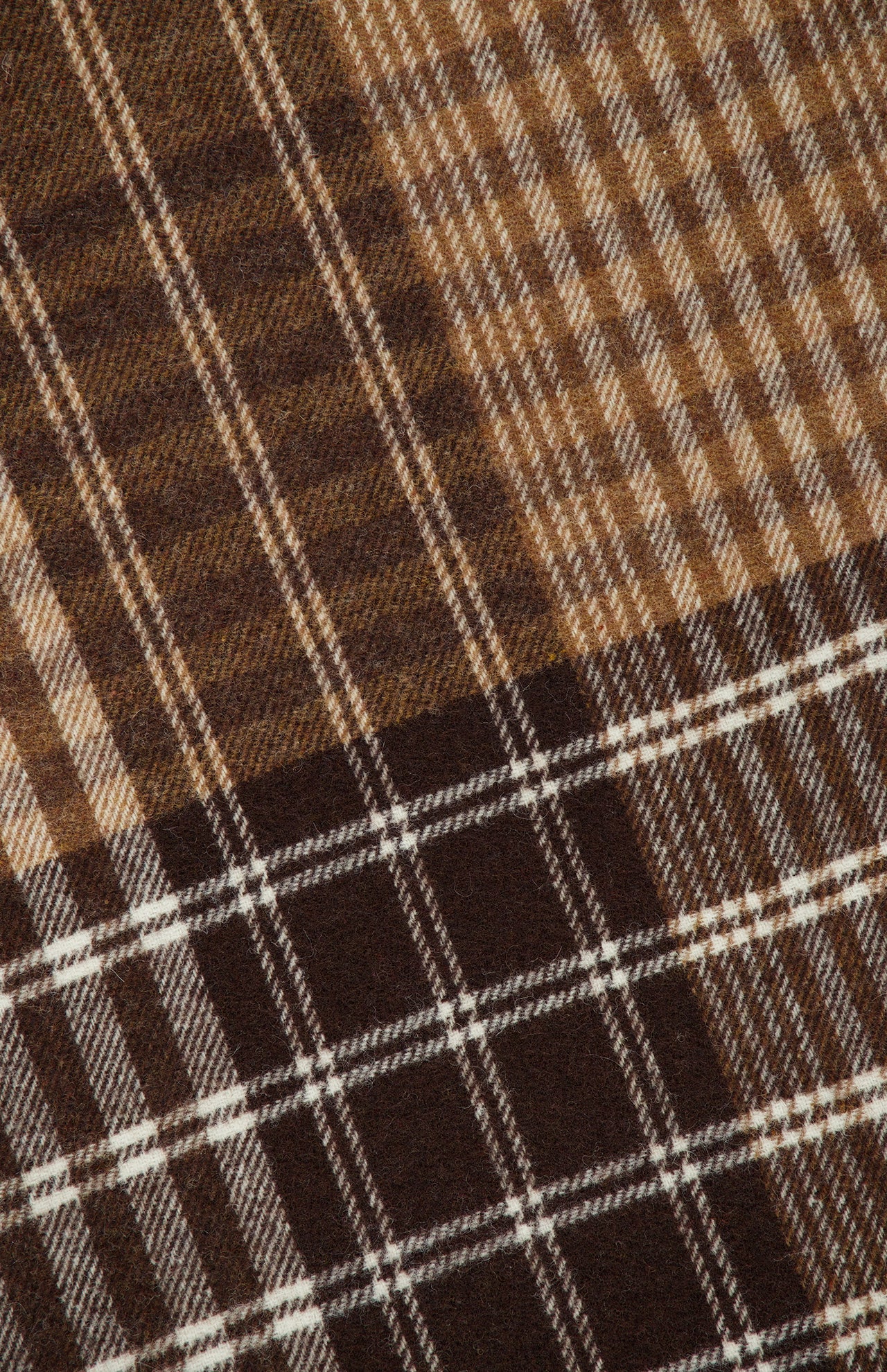 Close-up of the LES DEUX Signature Patchwork Check Scarf, showcasing intersecting horizontal and vertical lines in tan and cream that form a checkered pattern with varied shades and widths; crafted from soft wool, this scarf is finished with delicate fringe along the edge.
